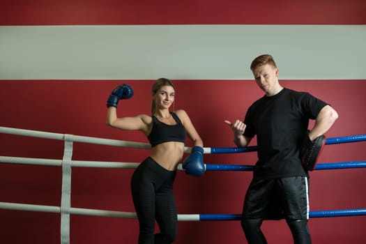 Sexy girl in boxing gloves and her boyfriend posing in a boxing ring