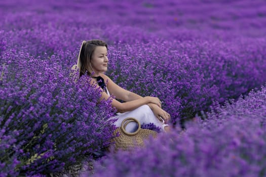 A woman sits in a field of purple flowers.