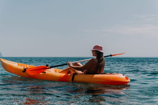 Happy smiling woman in kayak on ocean, paddling with wooden oar. Calm sea water and horizon in background