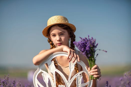 girl sitting field lavender and wearing a straw hat. She is smiling and holding a bouquet of flowers.