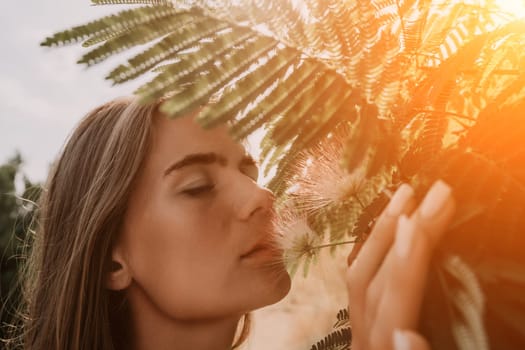 Beauty portrait of young woman closeup. Young girl smelling Chinese acacia pink blossoming flowers. Portrait of young woman in blooming spring, summer garden. Romantic vibe. Female and nature.
