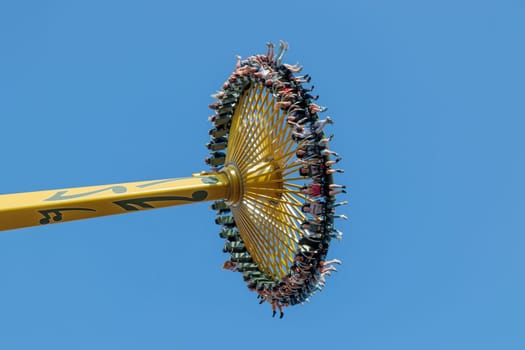 Helsinki, Finland - 19 July 2024: Linnanmaki Amusement Park, new roller coaster Swingi in motion, blue sky on a background, happy people