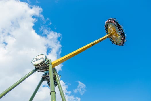 Helsinki, Finland - 19 July 2024: Linnanmaki Amusement Park, new roller coaster Swingi in motion, blue sky on a background, happy people