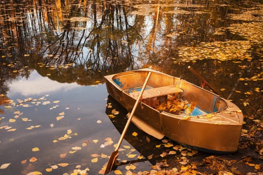 Golden wooden boat at beautiful autumn sunny day. Autumn peaceful landscape. with reflections