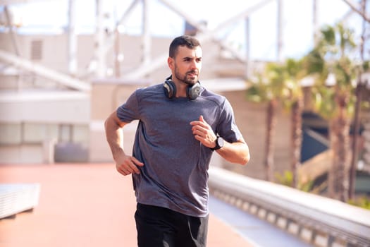 A photo of a young runner training with headphones on the city streets outdoors