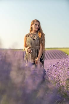 A woman is standing in a field of purple flowers, wearing a black dress and a black hat