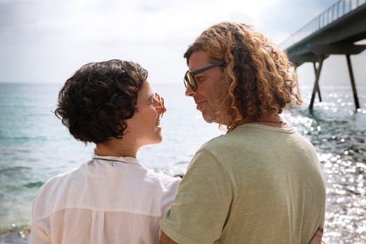Smiling couple with sunglasses enjoying a vacation looking at the sea.