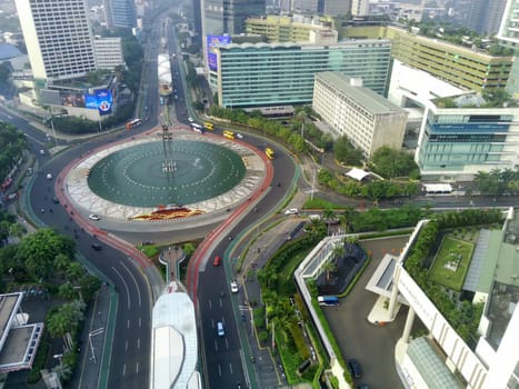 Aerial view of Bundaran HI, a bustling roundabout in Jakarta, Indonesia. Skyscrapers, traffic, and the Selamat Datang monument create a dynamic cityscape.