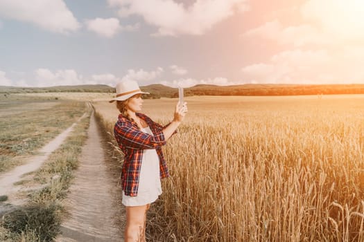 Woman farmer walks through a wheat field at sunset, touching green ears of wheat with his hands. Hand farmer is touching ears of wheat on field in sun, inspecting her harvest. Agricultural business.