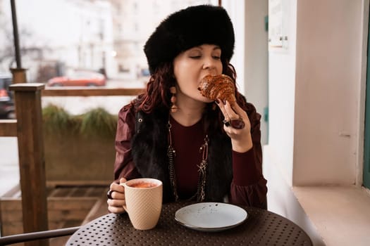 A woman in a red dress is sitting at a table with a plate of food and a cup of coffee