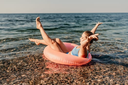 A woman is floating on a pink inflatable raft in the ocean. She is smiling and she is enjoying herself