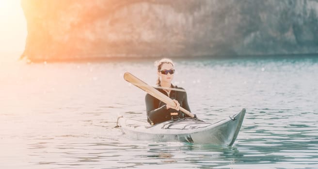 Happy smiling woman in kayak on ocean, paddling with wooden oar. Calm sea water and horizon in background