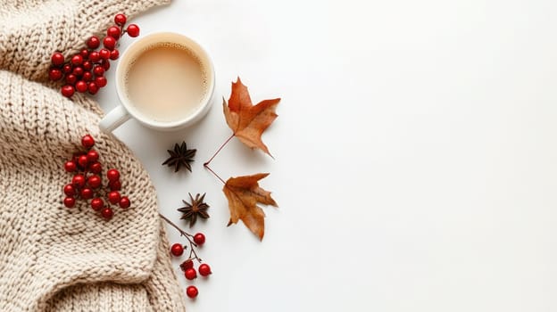 A warm beverage sits next to a knitted sweater, adorned with vibrant autumn leaves and red berries, creating a comforting seasonal atmosphere.