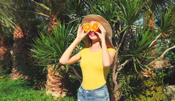 Summer, vacation, nutrition and vegetarian concept. Happy healthy cheerful young woman covering her eyes with slices of orange fruits and looking for something on beach with palm background