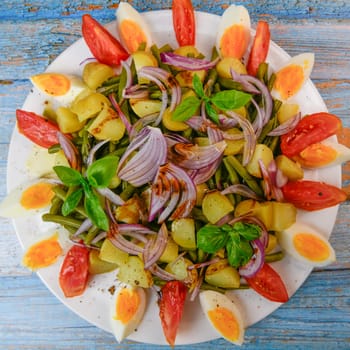 Fresh salad, green beans, small potatoes, egg, tomato, basil, red onions and balsamic vinaigrette. High quality photo