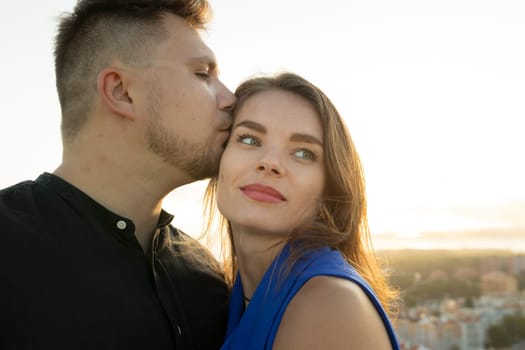 Young man kissing a woman on the forehead while enjoying a romantic moment outdoors