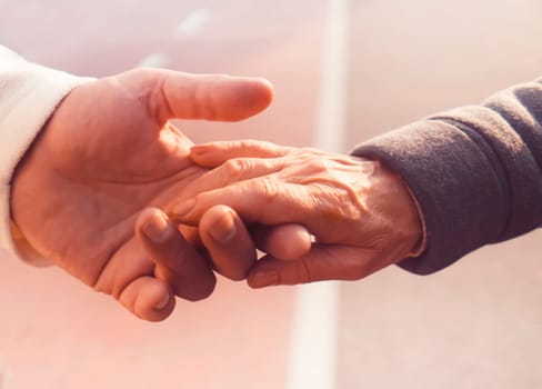 An elderly couple holds hands, grandparents show love and care, support each other throughout their lives, with mutual trust. A man holds the hand of an elderly beloved wife, close-up view.