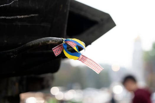 A ribbon with a Ukrainian blue and yellow flag attached to military equipment, a concept on the theme of the war and events in Ukraine, close-up view.