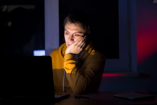 A man is developing his business, a young businessman is working on a startup concept at night, reading information on a laptop online at home.