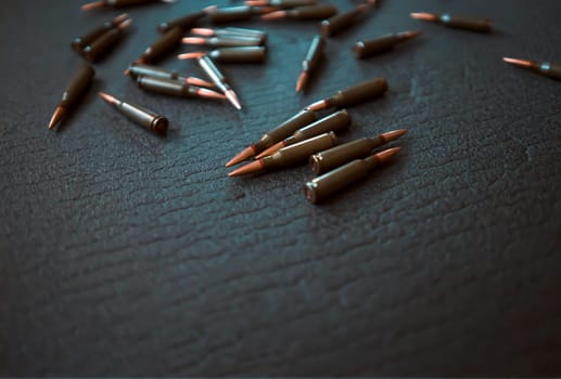 Cartridges from a Kalashnikov assault rifle close-up, lie on a dark gray background, a concept on the theme of war, resistance and crisis.