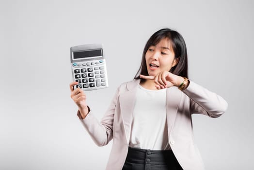 Tax day concept. Woman confident smiling holding calculator and finger point device, Portrait excited happy Asian female studio shot isolated on white background, Account and finance counting income