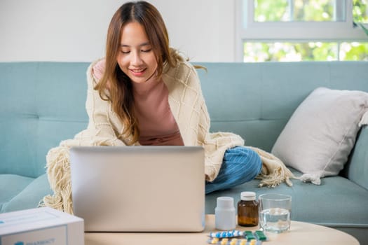 Sick young woman sit on sofa video call online with laptop consult with doctor at home, female covered blanket searching instructions for medical use medications in internet, healthcare and technology