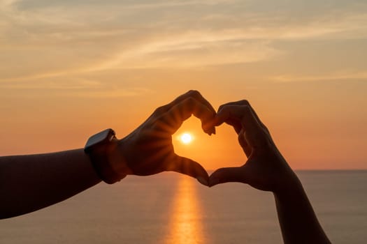 Hands heart sea sanset. Hands forming a heart shape made against the sun sky of a sunrise or sunset on a beach.