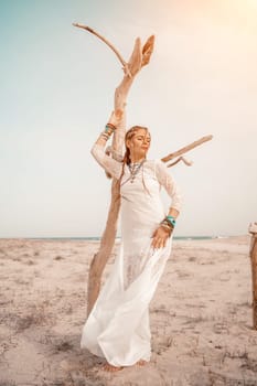 woman sea white dress. Model in boho style in a white long dress and silver jewelry on the beach. Her hair is braided, and there are many bracelets on her arms