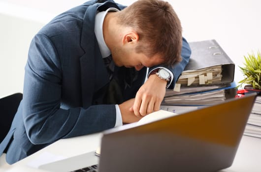 Tired office male clerk in suit take nap on table workplace full of exam papers. Sleepy white collar career frustration freelance employment fail study problem low energy down