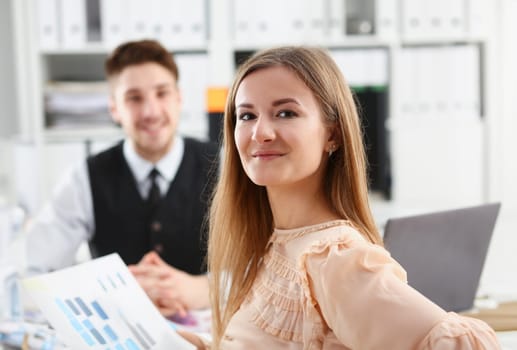 Beautiful smiling cheerful girl at workplace look in camera with colleagues group in background. White collar worker at workspace job offer modern lifestyle client visit profession train concept