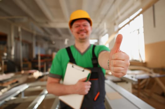 Smiling worker in yellow helmet show confirm sign with thumb up at arm portrait. Manual job DIY inspiration joinery startup idea fix shop hard hat industrial education profession career concept