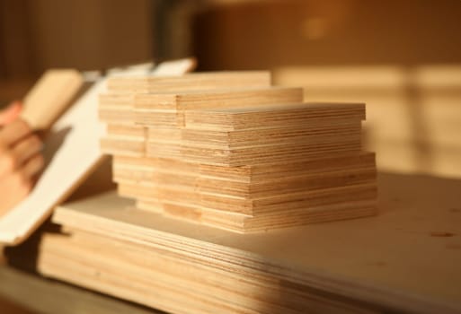 Wooden bars lying in a row closeup with manual worker in background. DIY job, inspiration, improvement, fix shop, powersaw bench, joinery startup, workplace idea, career, ruler, industrial education