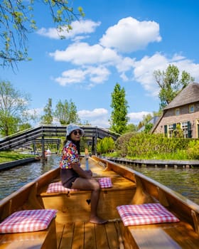 Asian women visit Giethoorn Netherlands, Asian female visit the village with a boat, view of the famous village with canals and rustic thatched roof houses in the Netherlands alongside the canals