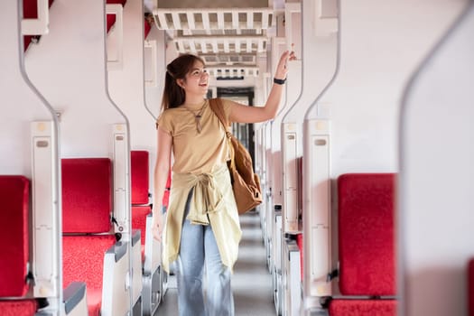 Young woman looking for a place to store her luggage in the train Vacation holiday, tourism, travel, interior of modern train, rail transport concept.