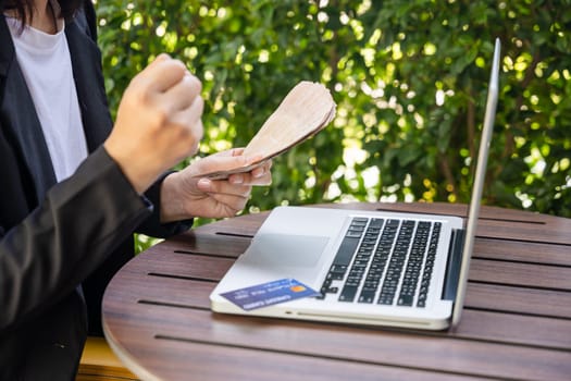 Woman using working and shopping, Online e-commerce, internet banking, Hands of businesswoman holding thai money and credit card on laptop computer, technology finance