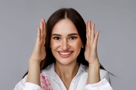 young pretty woman covering her ears by hands on grey background.