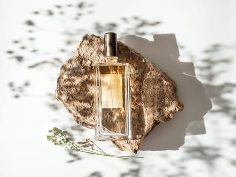 Mockup geometric shape stone podium with glass perfume bottle top view. Stone shape with gypsophila flowers shades over white background. Flat lay. Can use as perfume and cosmetic mock up