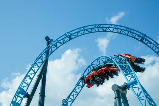 Helsinki, Finland - 19 AUGUST 2024: Linnanmaki amusement park with roller coaster Taiga in motion, blue sky on a background, happy people
