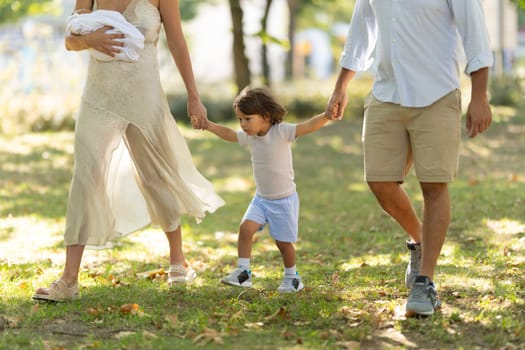 Young family enjoys a leisurely stroll in the park, embracing the joys of parenthood and creating cherished memories