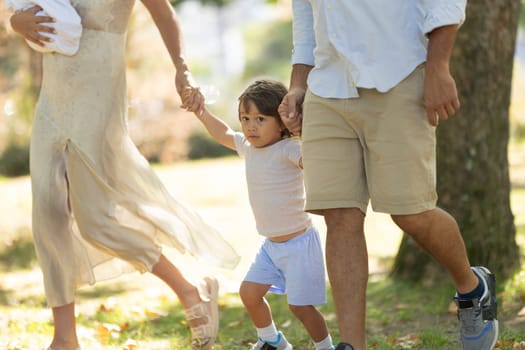 Young family enjoys a sunny day out, taking a leisurely stroll through the park with their two children