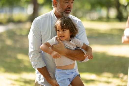 Father is holding his young son in his arms while spending time together in a park