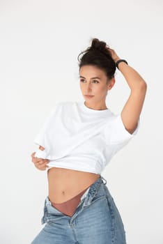Happy beautiful girl posing in a new hot summer look. Wearing blue jeans and white waistcoat.