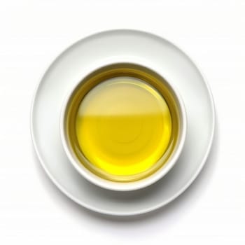Top view of a bowl of clear yellow liquid, possibly oil or broth, on a white surface