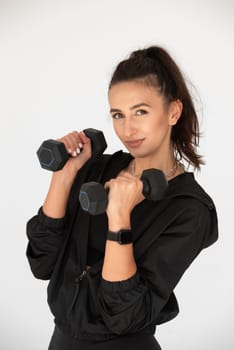 Young girl posing with dumbbells for power training, indoors. athlete wearing black leggings and shirt.
