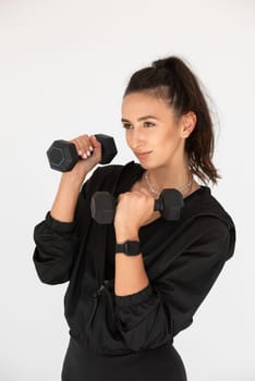 Young girl posing with dumbbells for power training, indoors. athlete wearing black leggings and shirt.
