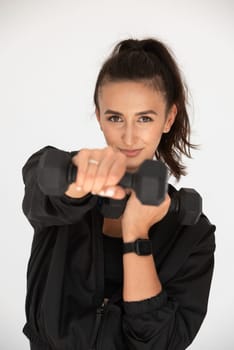 Young girl posing with dumbbells for power training, indoors. athlete wearing black leggings and shirt.