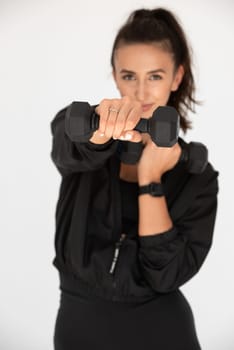 Young girl posing with dumbbells for power training, indoors. athlete wearing black leggings and shirt.