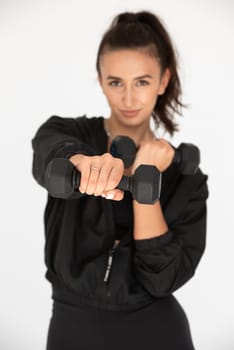 Young girl posing with dumbbells for power training, indoors. athlete wearing black leggings and shirt.