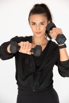 Young girl posing with dumbbells for power training, indoors. athlete wearing black leggings and shirt.