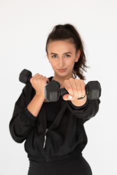 Young girl posing with dumbbells for power training, indoors. athlete wearing black leggings and shirt.